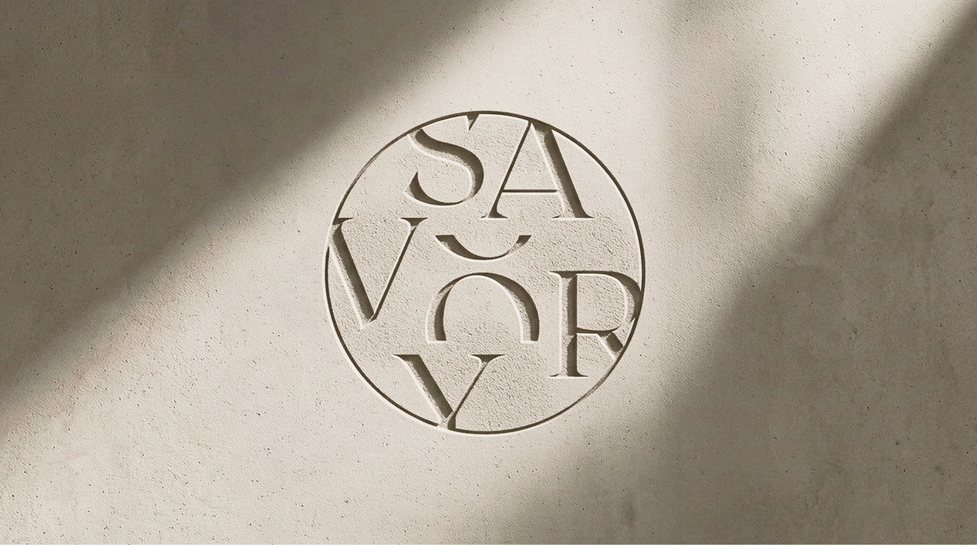 Circular SAVORY emblem embossed into a textured wall in warm sunlight